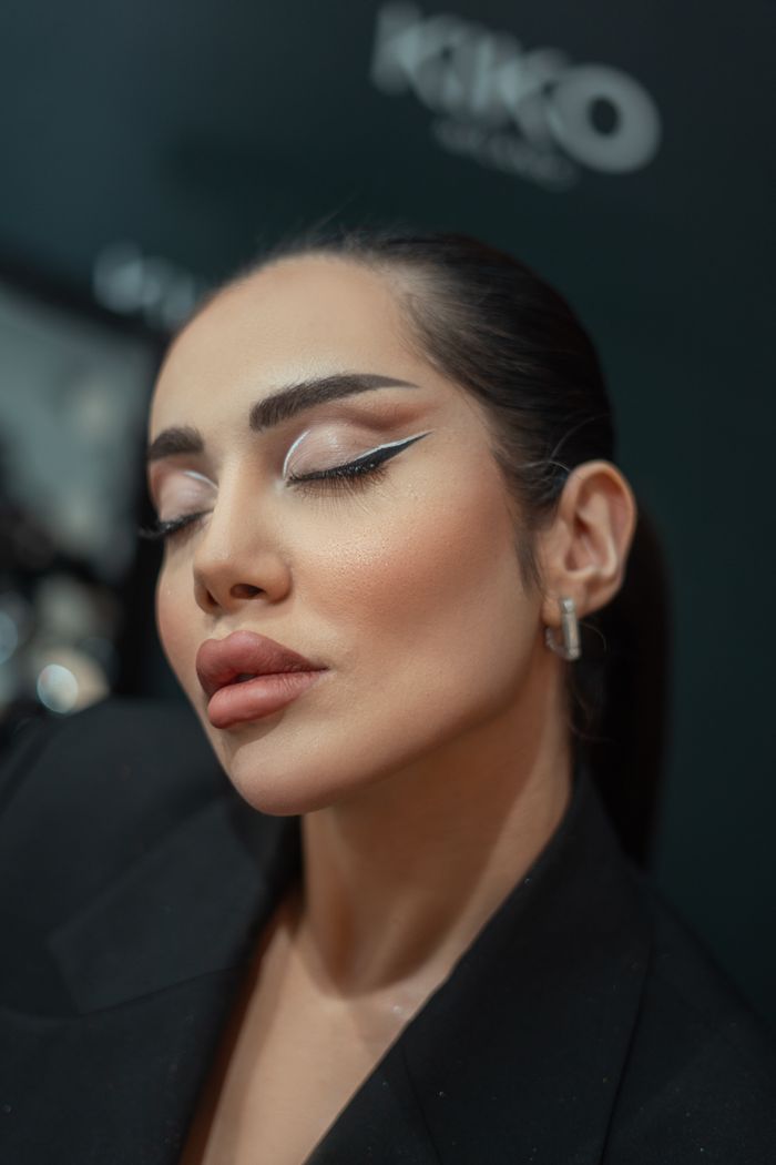 Close-up portrait of a woman with bold makeup and closed eyes, showcasing elegance and style.